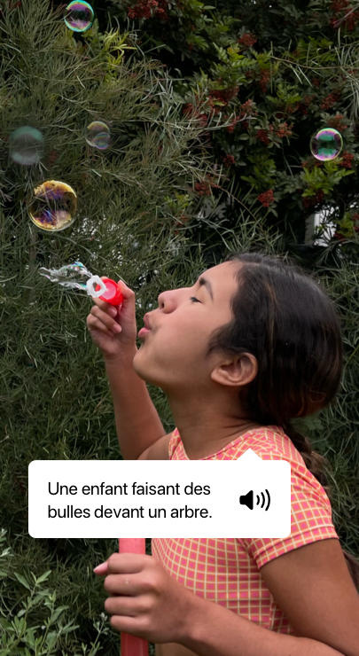 VoiceOver décrivant une photo et affichant la sortie vocale. ‘Une enfant faisant des bulles devant un arbre.’