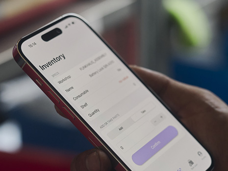 Zbliżenie na iPhone’a w ręku. Na ekranie wyświetlane jest śledzenie zapasów.